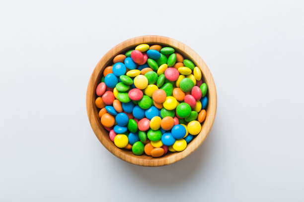 五颜六色的糖果放在碗里，背景是彩色的。生日和节日的概念。带复制空间的俯视图图片下载