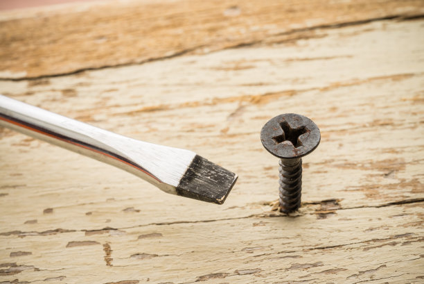 这个工具用错了。螺丝和螺丝刀在旧的木制背景。图片下载