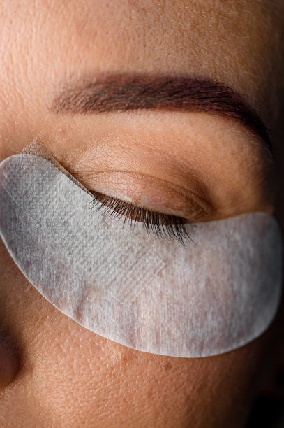 漂亮的女性脸部特写，眼睛下面有一次性纸贴片。睫毛延伸图片下载