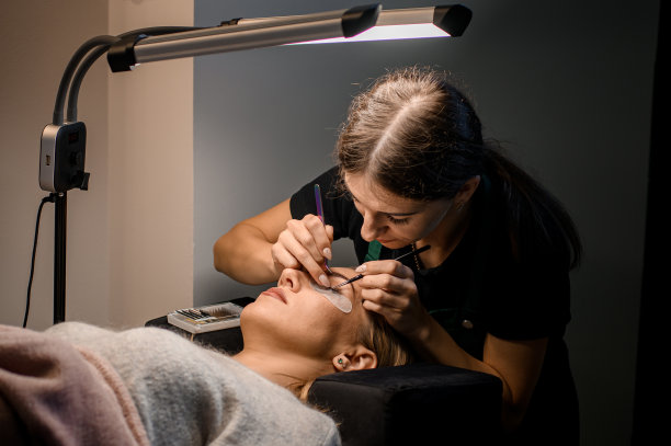 专业女美容师在美容院为女顾客做睫毛加长。图片下载