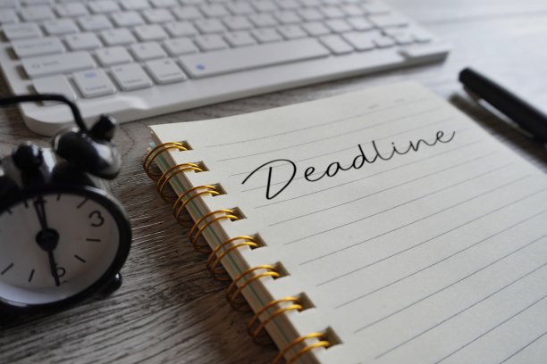时钟、键盘、笔和写有截止日期的笔记本。图片下载