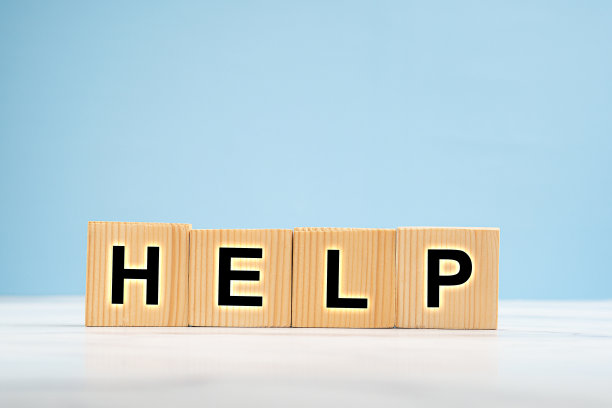 在蓝色背景的大理石地板上，有字母HELP的木制立方体图片下载