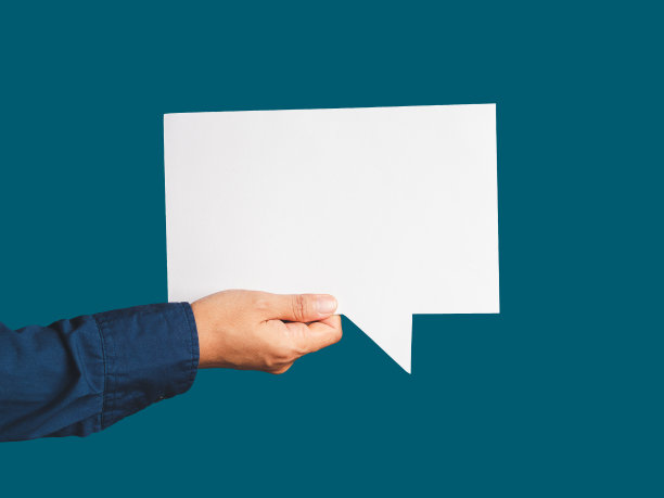 在蓝色背景下，手拿着一个白色的演讲泡泡的特写图片下载