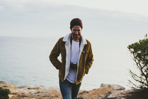 一个年轻人走在海边的悬崖上图片下载