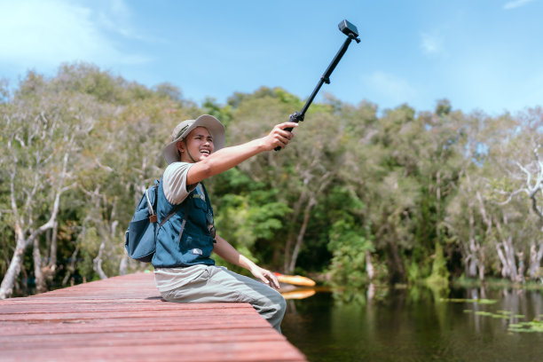 亚洲人坐在桥上旅行，拍摄有趣的照片和视频。河流和红树林图片下载