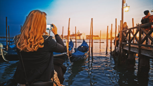 金发女子在黄昏时分用智能手机拍照图片下载