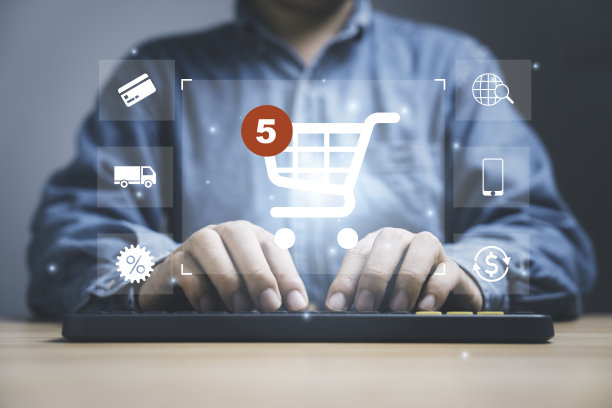 商人在电脑键盘上打字，用虚拟购物车和电子商务图标，如购物车，送货车，销售百分比进行网上购物的概念。图片下载