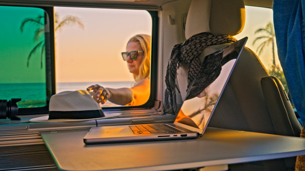 一个女人在海滩上从露营车窗口拿起帽子图片下载