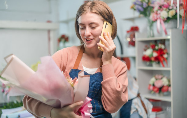 年轻的花店女老板用手提电脑打电话。亚洲女性视频博主网红或中小企业老板微笑着在家用摄像机自拍。图片下载