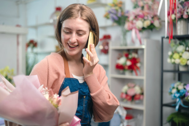 年轻的花店女老板用手提电脑打电话。亚洲女性视频博主网红或中小企业老板微笑着在家用摄像机自拍。图片下载
