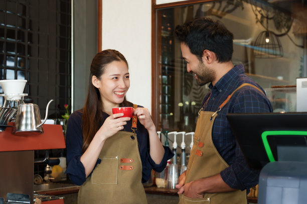 亚洲夫妇一起开了这家新咖啡馆，站在那里谈论开业第一天店应该解决什么问题，拿着一杯咖啡喝着，表情严肃。图片下载