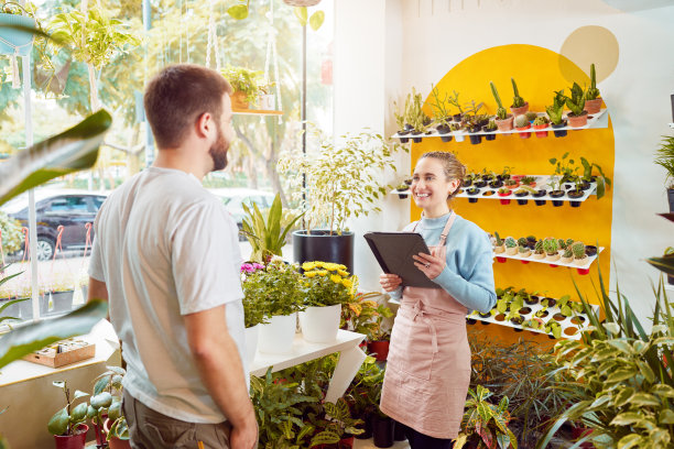 肖像白人女雇员植物店老板为顾客服务图片下载