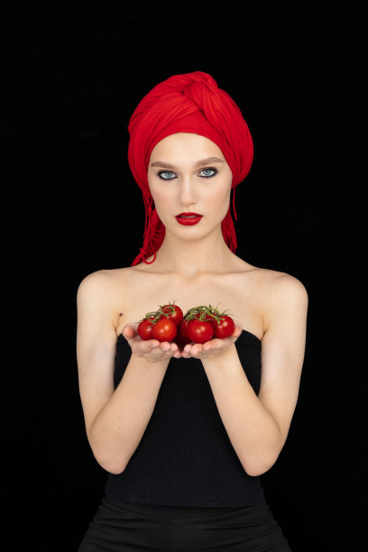 美丽的特写肖像的年轻女子与番茄。健康食品和蔬菜的概念。护肤美容。维生素和矿物质图片下载