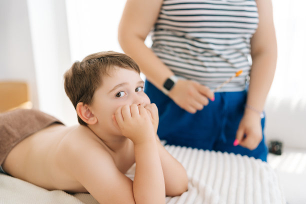 漂亮的五岁男孩躺在沙发上等待小儿按摩师，看着相机的照片。可爱的孩子等待治疗的侧视图图片下载