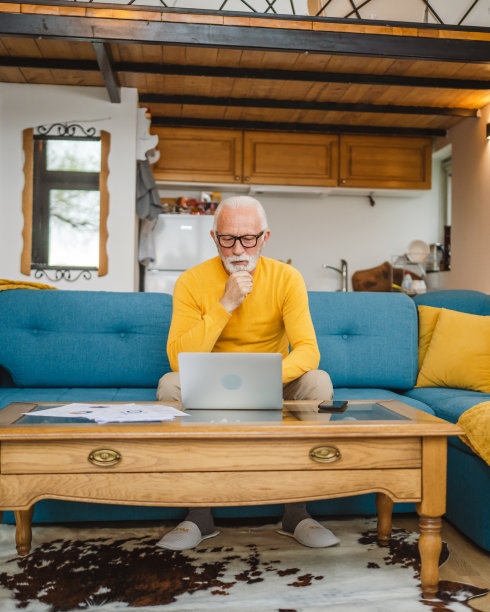 一位年长的白种人在家里用笔记本电脑工作图片下载