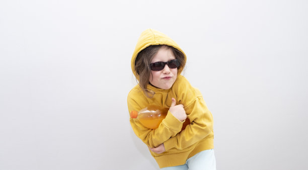 表情和手势。女孩微笑着，手里拿着一瓶橙汁汽水。一个六岁白人女孩的肖像，复印的空间。图片下载