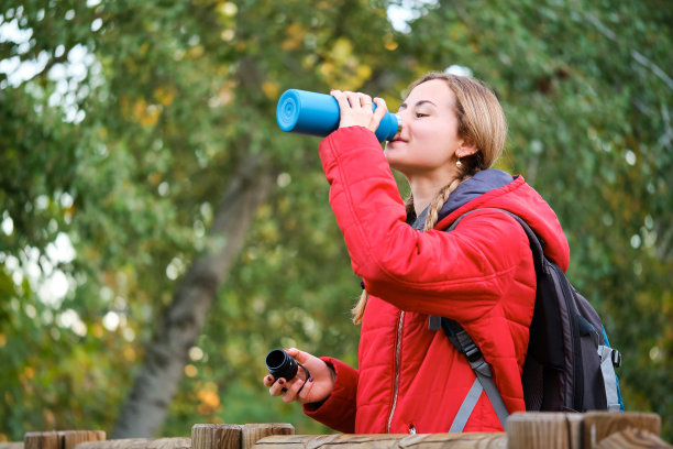 徒步旅行者从水壶里喝水，凝视着森林里的景色。图片下载