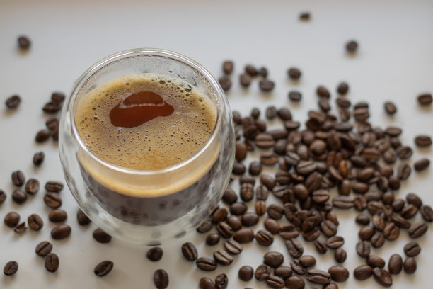 玻璃杯与美式咖啡在咖啡豆的背景。图片下载