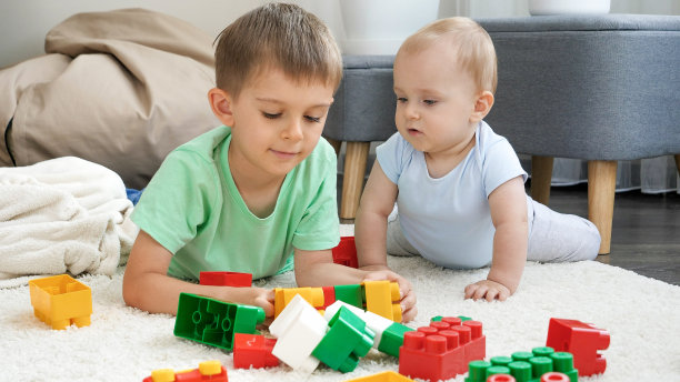 小男孩看着他的哥哥玩玩具和积木图片下载