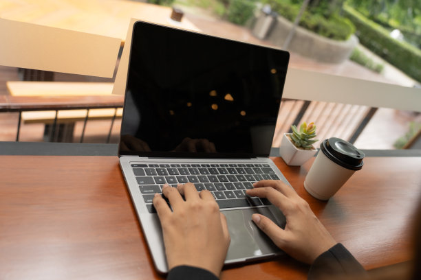 一杯咖啡在她身边，一个年轻女子的手优雅地操纵着笔记本电脑，沉浸在网上购物的便利和兴奋中，她探索着一个充满无限可能性的世界。图片下载