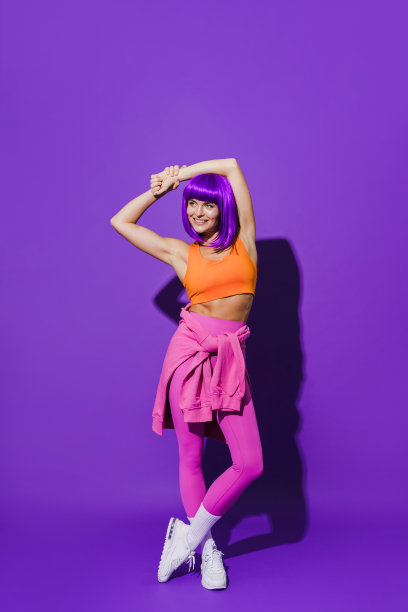 欢快的女人穿着五颜六色的运动服坐在紫色的背景下图片下载