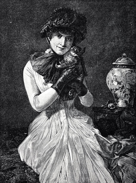 一个年轻漂亮的女人把一只小猫放在她的脸颊上图片下载