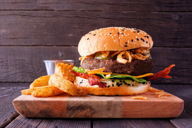 汉堡里有奶酪、培根和脆洋葱。桌景映衬着暗木。图片下载