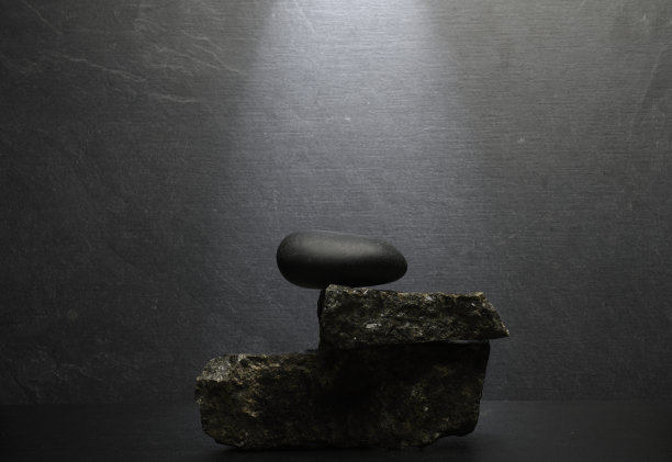 深灰色背景上的黑色石头作为产品展示的讲台背景。图片下载