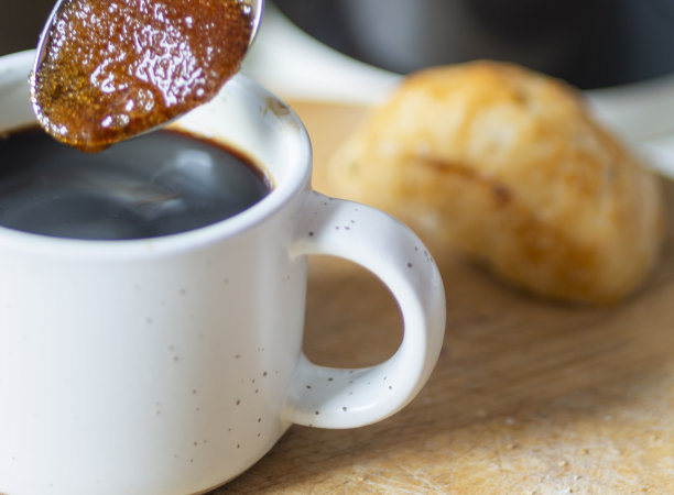 在英国伍斯特郡的一个家庭厨房里，用银茶匙放糖，从一个小杯子里吸收热的意式浓缩咖啡。图片下载