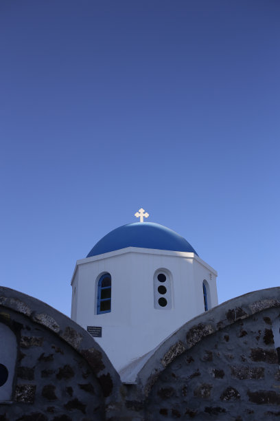 在晴朗的蓝色天空下，希腊一座教堂的蓝色圆顶建筑顶部闪耀着东正教十字架图片下载