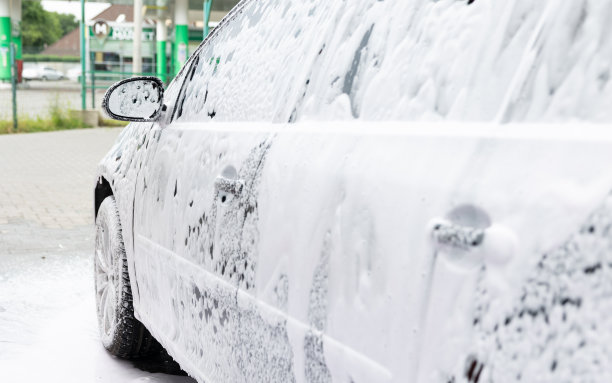在自助洗车店，这辆车被白色泡沫覆盖。图片下载