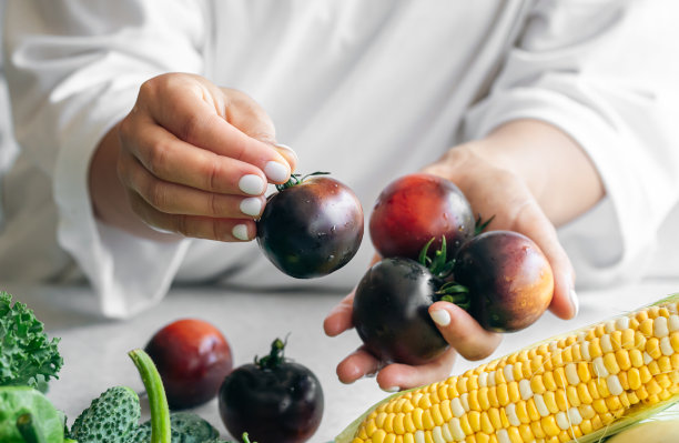 女性手中的黑番茄特写，在厨房做饭。图片下载