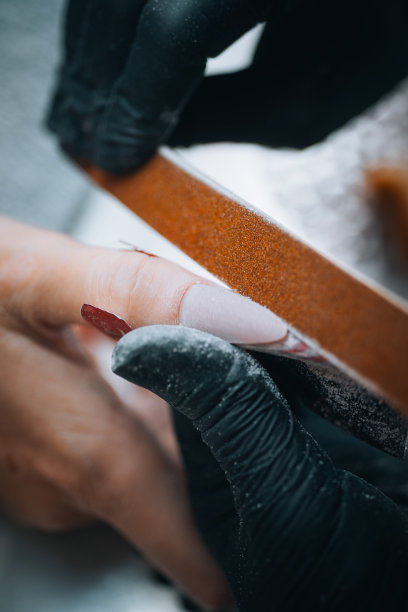 一个美甲师用指甲锉精确地锉女人手上的指甲的特写。图片下载