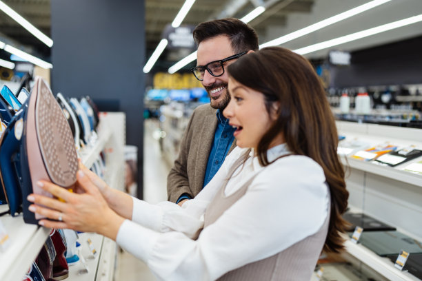 年轻夫妇在现代科技商店买东西。图片下载