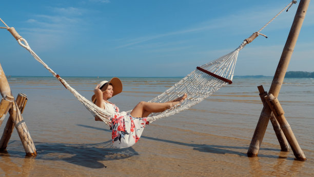 在海边的吊床上放松的女人。图片下载