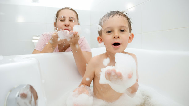搞笑的照片，男孩和妈妈在浴室玩耍，吹肥皂泡和泡沫图片下载