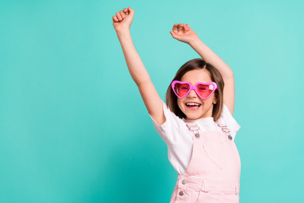 可爱甜美的女生穿着粉红色整体眼镜跳舞空空间微笑孤立的蓝绿色背景照片图片下载