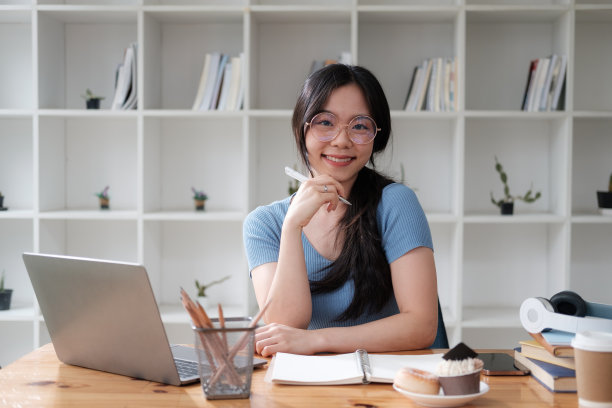 一位微笑的年轻亚洲学生正在用笔记本电脑学习在线课程，准备期中考试。图片下载