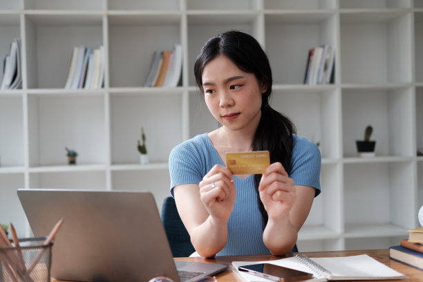 快乐的年轻女性手里拿着信用卡和智能手机，进行网上支付。图片下载