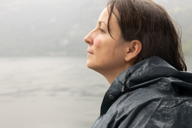 一个面颊上有胎记的年轻女子的巨幅肖像，背景是水图片下载