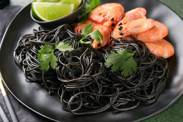 黑色的意大利面，意大利面虾在黑色的盘子上，黑色的混凝土桌子背景。鱿鱼墨对虾意面。意大利海鲜。绿石桌俯视图。地中海传统菜肴。图片下载