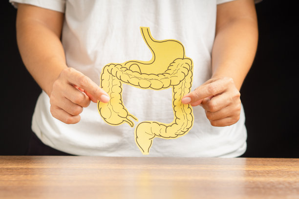 手拿着纸做的大肠形状，站在黑色背景上图片下载