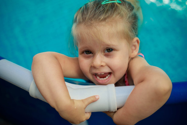 小女孩靠在泳池栅栏上的特写照片。图片下载