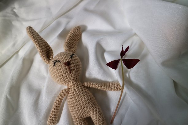 白布背景上的钩针兔子。针织玩具，手工制作，针线活，小兔子。图片下载