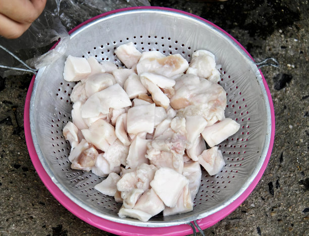 一张照片上，一个人拿着一个装满鸡肉的滤嘴，一个装满大块鸡肉的过滤器，坐在柜台上。图片下载