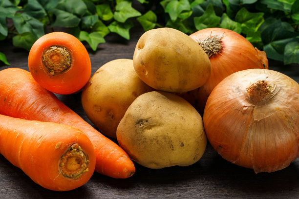 木桌上有未削皮的生土豆、洋葱和胡萝卜图片下载