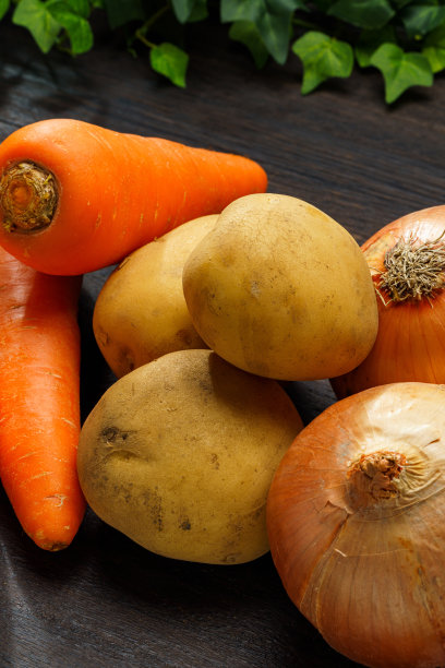 木桌上有未削皮的生土豆、洋葱和胡萝卜图片下载