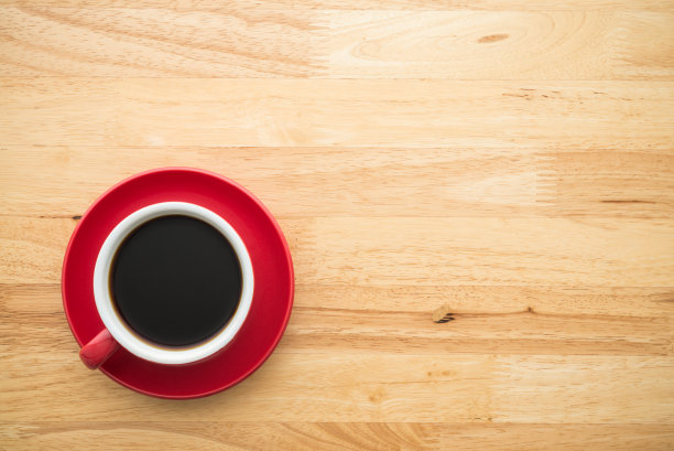 木桌背景上红色滴咖啡杯的顶视图。图片下载