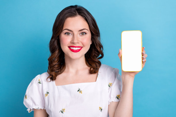 照片肖像迷人的年轻女子小工具白屏幕空白空间穿着时髦的蓝色衣服孤立在粉红色的背景图片下载