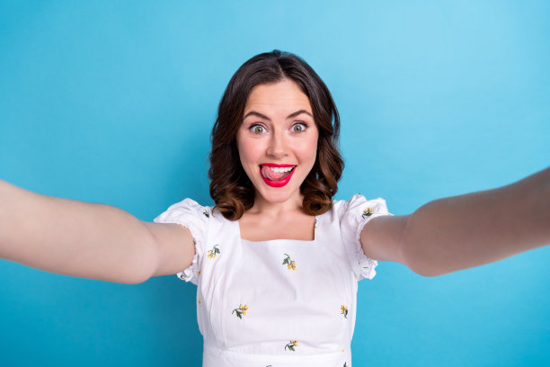 疯狂积极的漂亮女士的照片让自拍舌舔牙齿红色唇膏润发孤立在蓝色的背景图片下载